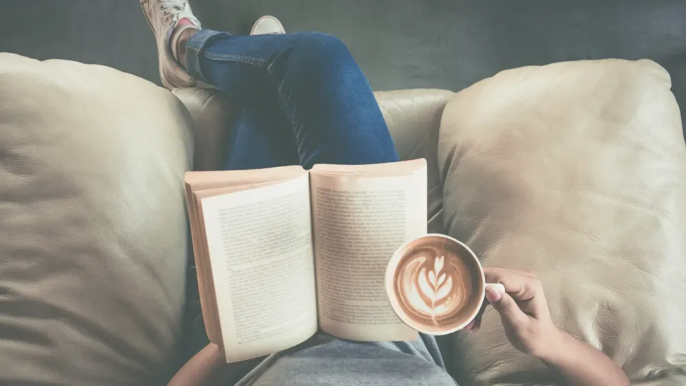 person reading book with coffee